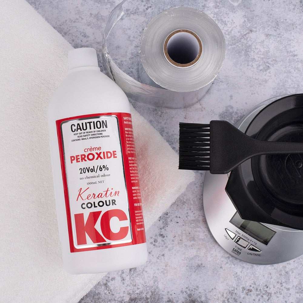 Keratin Colour KC hair color product with a brush and scale on a gray surface