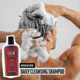 Person washing hair with American Crew Daily Cleansing Shampoo, product displayed on the left.